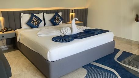 Bedroom at Hotel Kyzen HiTech City with a king bed on a blue decorative carpet.